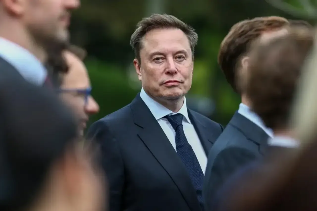 Retrato de Elon Musk vistiendo traje formal y corbata oscura en un evento empresarial.