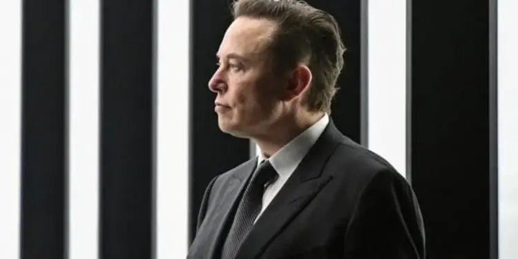 Retrato de perfil de un empresario con traje oscuro y corbata ante un fondo de líneas verticales blancas y negras.