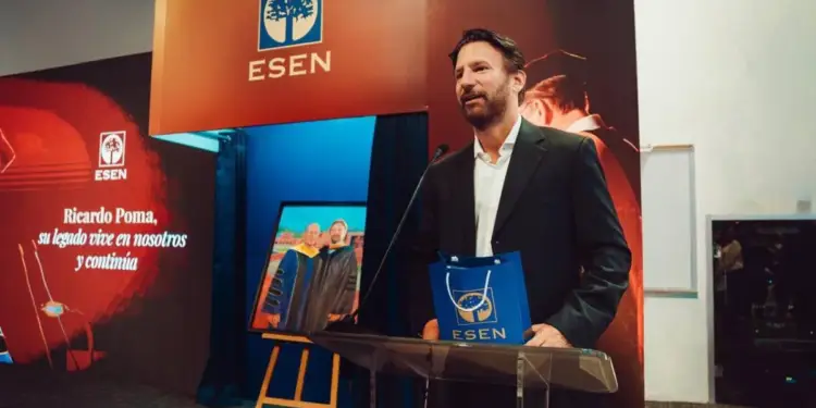Un hombre con traje oscuro habla en un podio frente a un fondo con el logo de ESEN y una imagen de dos graduados.