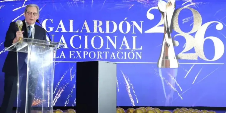 Hombre de traje hablando en un atril frente a una pantalla azul que dice Galardón Nacional de la Exportación