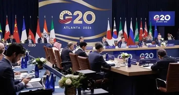 Delegados internacionales sentados en mesas de conferencias durante la cumbre del G20 Atlanta 2026 con banderas de fondo