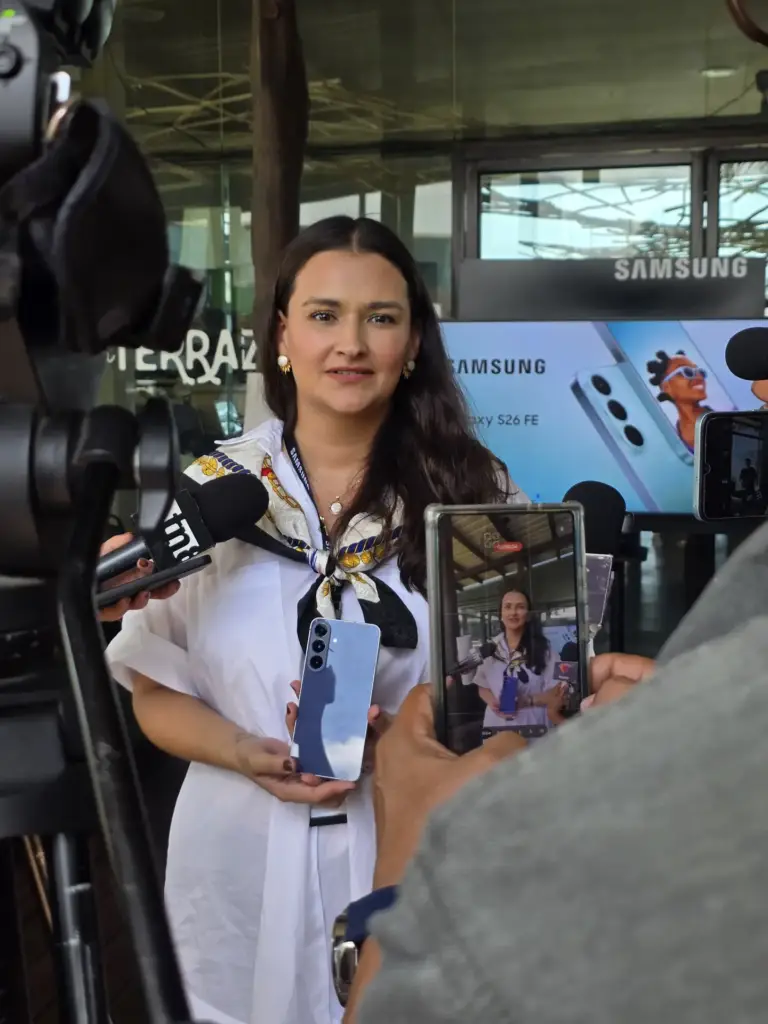 Una vocera de Samsung muestra la parte trasera del Galaxy S26 FE con su cámara triple frente a micrófonos de prensa