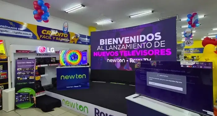 Interior de una tienda con un escenario anunciando el lanzamiento de nuevos televisores de marcas comerciales.