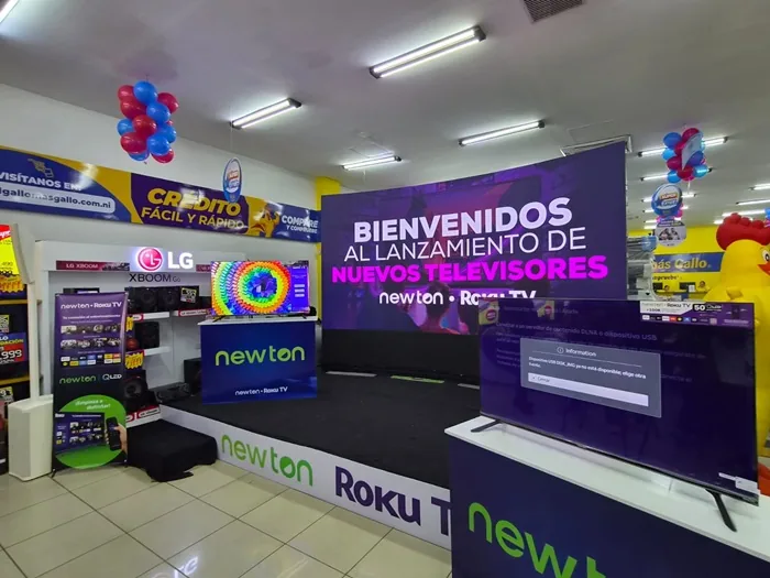 Interior de una tienda con un escenario anunciando el lanzamiento de nuevos televisores de marcas comerciales.