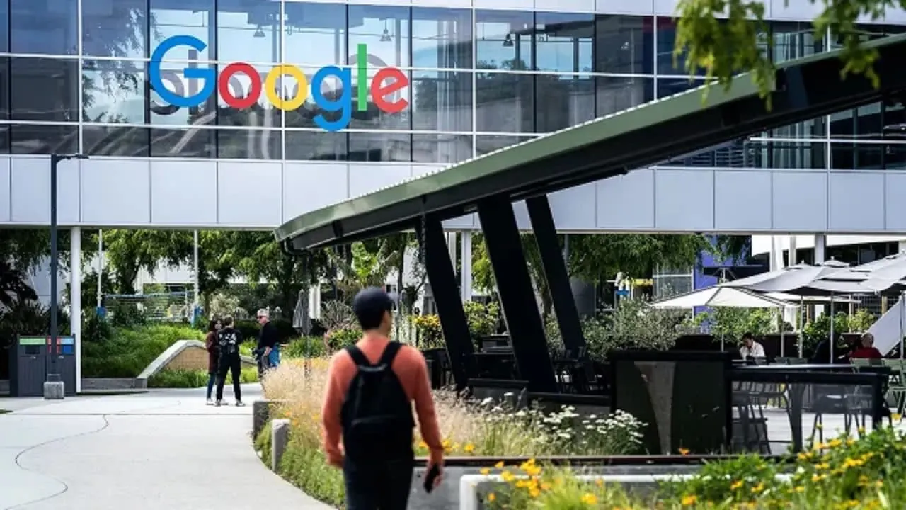 Vista exterior del edificio con el logotipo de Google y personas caminando por el campus.