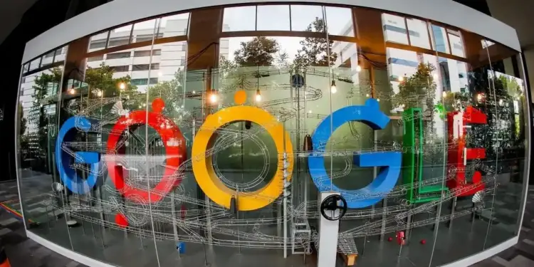 Gran letrero de Google rodeado por un intrincado circuito de canicas dentro de una estructura de cristal en una oficina.