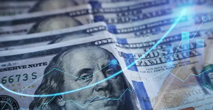 Primer plano de billetes de cien dólares superpuestos con gráficos estadísticos azules brillantes de crecimiento.