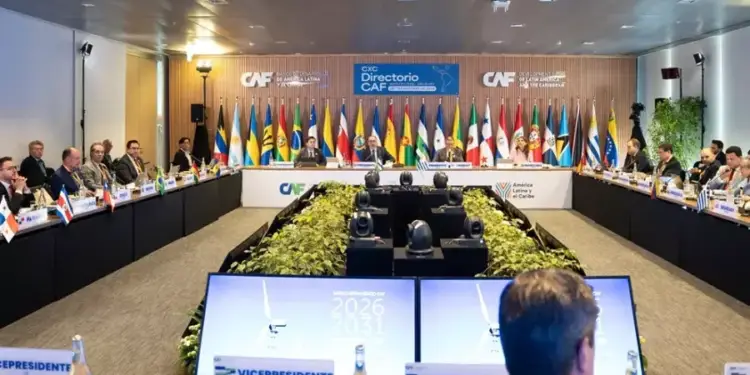 Amplia sala de conferencias con una gran mesa en U, múltiples delegados y banderas internacionales al fondo.