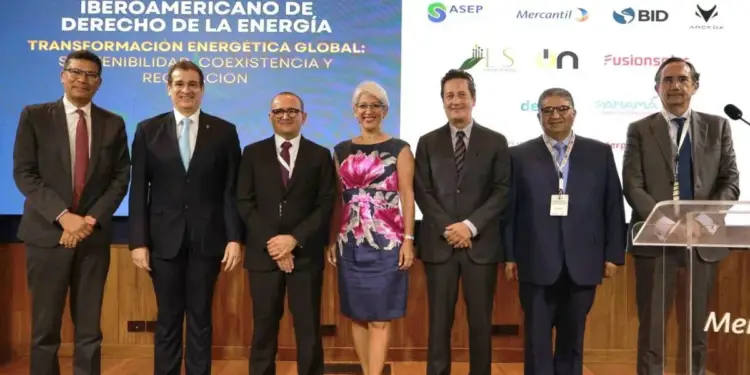 Grupo de profesionales posando para una foto en un evento sobre derecho energético, con un fondo que muestra el título del congreso y logos de patrocinadores.