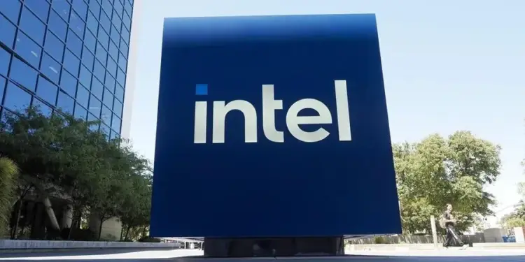 Gran cartel azul con el logotipo de intel frente a un edificio corporativo moderno y árboles en un día soleado.