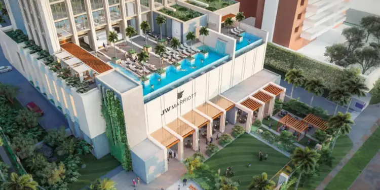 Vista aérea de un moderno hotel JW Marriott con piscinas en la azotea, jardines verticales y una entrada principal con pérgolas. Personas disfrutan de las instalaciones y áreas verdes.