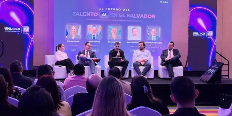 Panel de expertos discutiendo el futuro del talento en IA en El Salvador, con audiencia. Pantalla muestra 'EL FUTURO DEL TALENTO AI EN EL SALVADOR'.