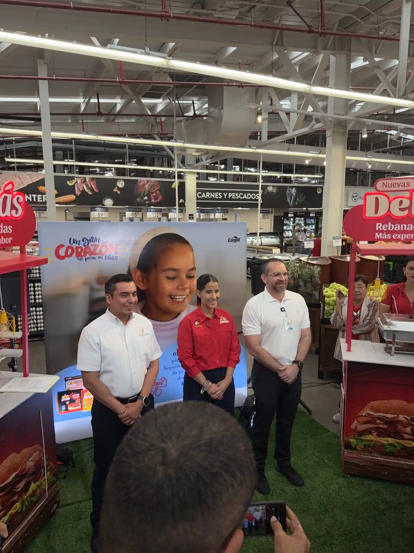 Representantes del Banco de Alimentos de Nicaragua, Cargill y Walmart Nicaragua posan frente al banner de la campaña Un gran corazón se pesa en libras dentro de un supermercado Walmart en Managua