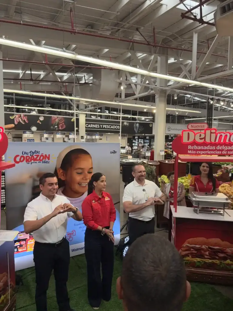 Voceros de la campaña forman un corazón con las manos junto a un stand de la marca Delicia en un supermercado de Managua