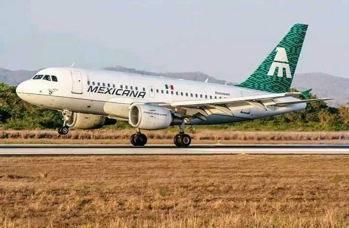 Avión comercial de la aerolínea Mexicana de aviación aterrizando en una pista rodeada de vegetación y montañas.