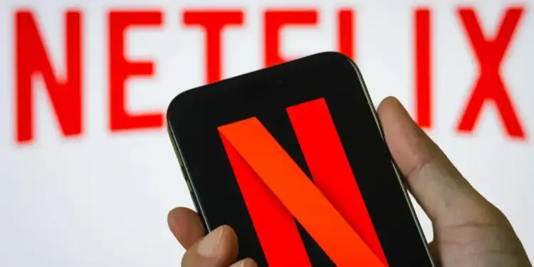 Mano sosteniendo un teléfono inteligente que muestra el logotipo rojo de la plataforma en su pantalla.