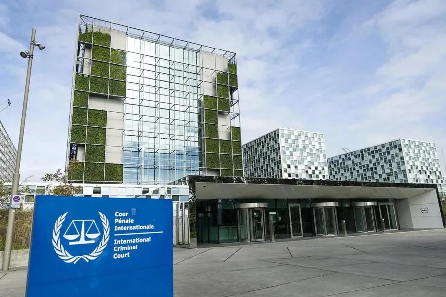 Edificio moderno con fachada de cristal y jardines verticales, señalización de la Corte Penal Internacional visible en primer plano.
