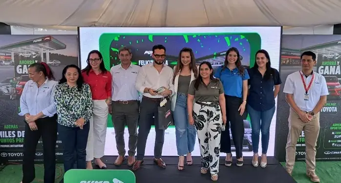 Grupo de nueve personas posando sonrientes en un escenario frente a una pantalla con la marca Puma Pris.
