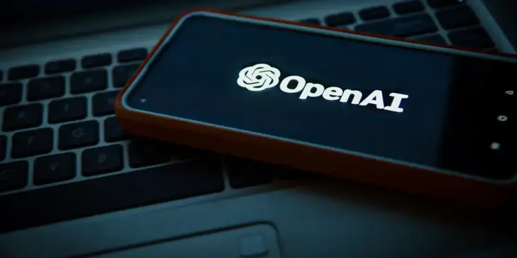 Smartphone con estuche naranja mostrando el logotipo brillante de OpenAI sobre un teclado de computadora portátil.