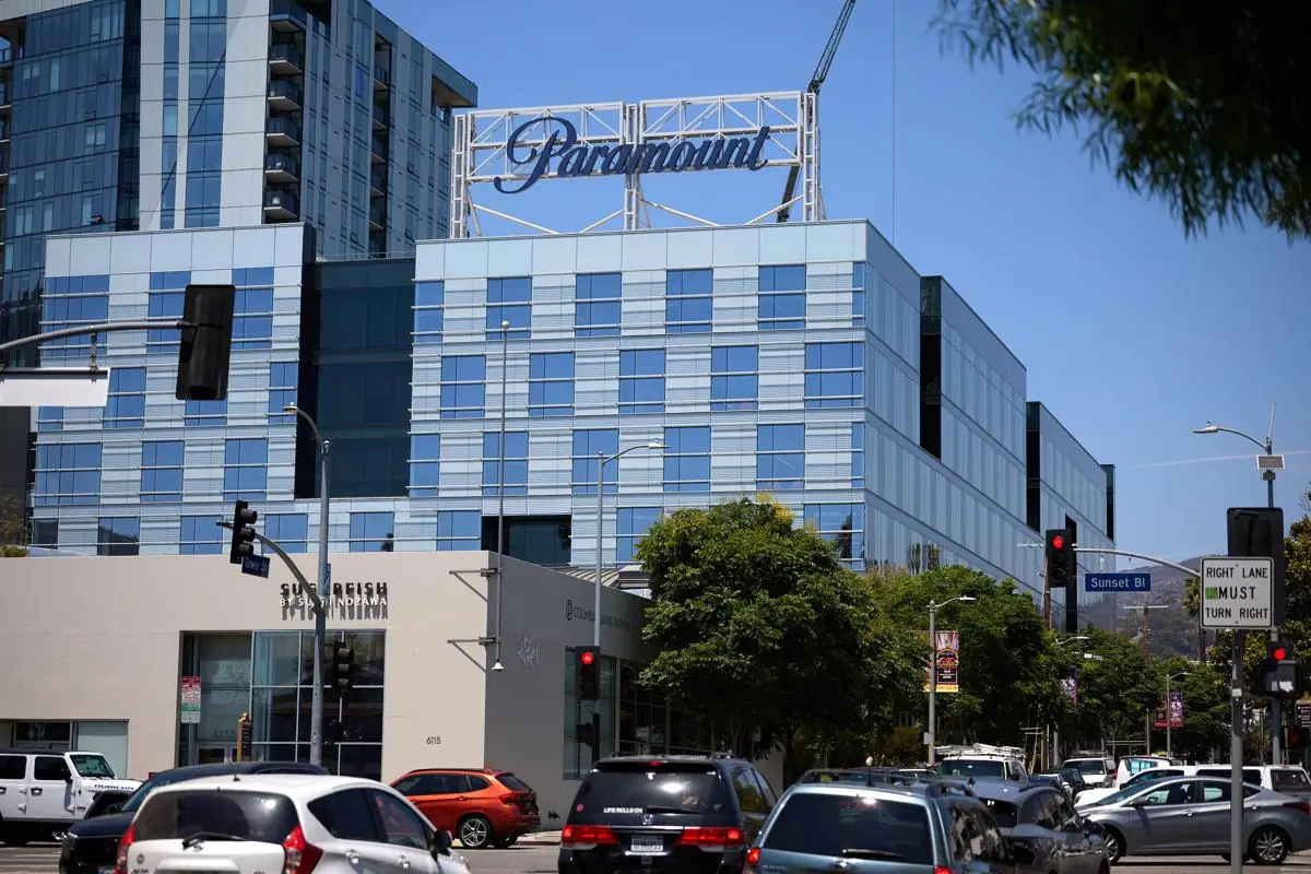 Vista exterior de un edificio moderno de oficinas con el logotipo de Paramount en la azotea y tráfico vehicular en la calle.