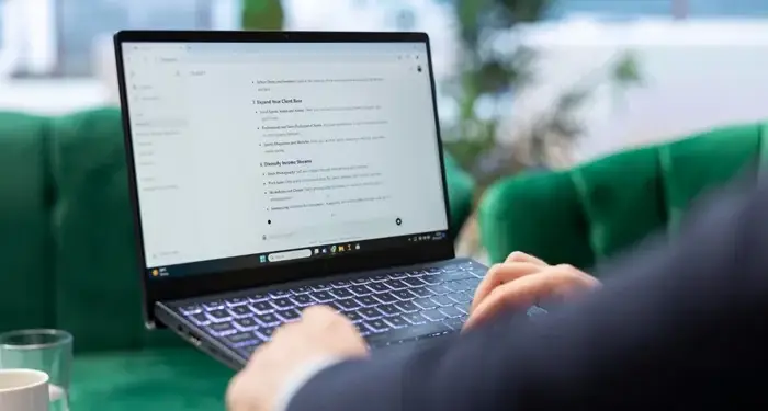Persona con traje trabajando en una laptop con texto en la pantalla en una oficina moderna con sillones verdes.