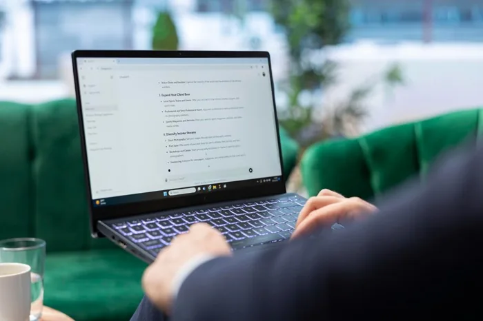 Persona con traje trabajando en una laptop con texto en la pantalla en una oficina moderna con sillones verdes.