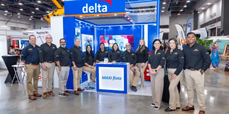 Grupo de profesionales en camisas negras y pantalones caqui posando frente a un stand azul y blanco en una feria comercial.