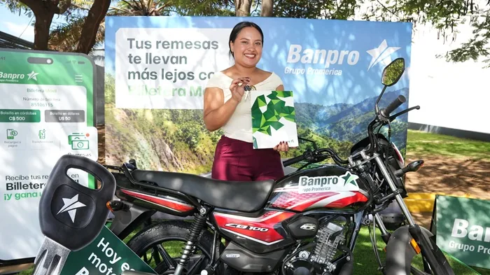 Mujer sonriente sosteniendo llaves y documentos frente a una motocicleta negra y roja con el logotipo de Banpro.