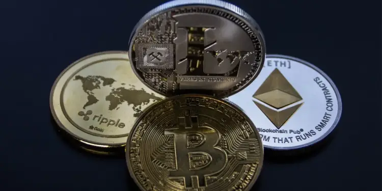 Primer plano de varias criptomonedas físicas: Bitcoin, Ethereum, Ripple y Litecoin, dispuestas sobre una superficie oscura. Representan activos digitales y el futuro financiero.