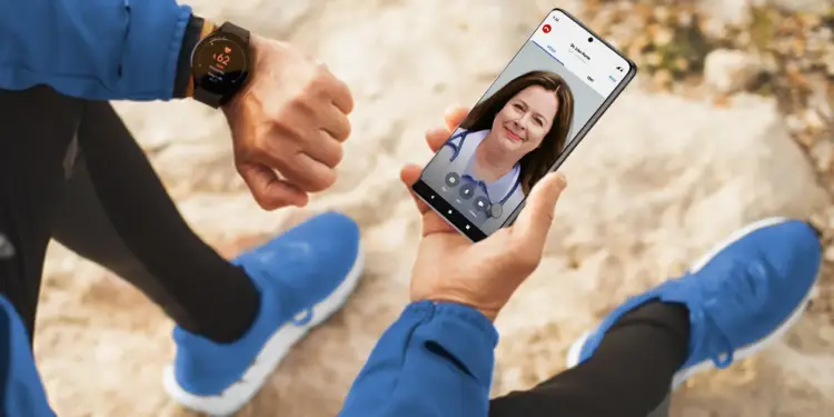 Persona sentada en rocas usando un reloj inteligente y realizando una videollamada médica en el teléfono móvil.