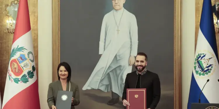 Dos autoridades muestran documentos firmados frente a las banderas de Perú y El Salvador.