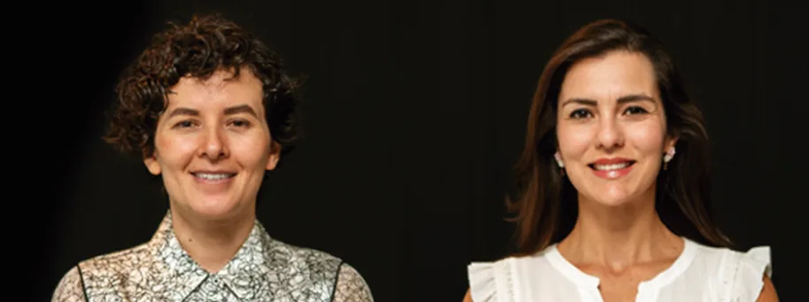 Dos mujeres profesionales sonrientes. Una con cabello rizado y camisa estampada, otra con cabello liso y blusa blanca.