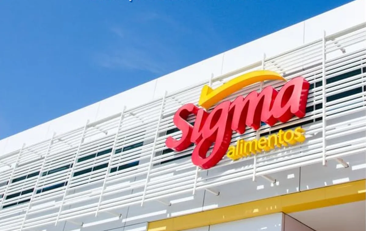 Fachada de un edificio moderno con el logotipo rojo y amarillo de Sigma Alimentos en letras tridimensionales, bajo un cielo azul claro.