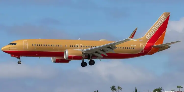 Avión comercial de Southwest Airlines con fuselaje dorado y franjas rojas y naranjas en la cola, aterrizando o despegando con el tren de aterrizaje desplegado.
