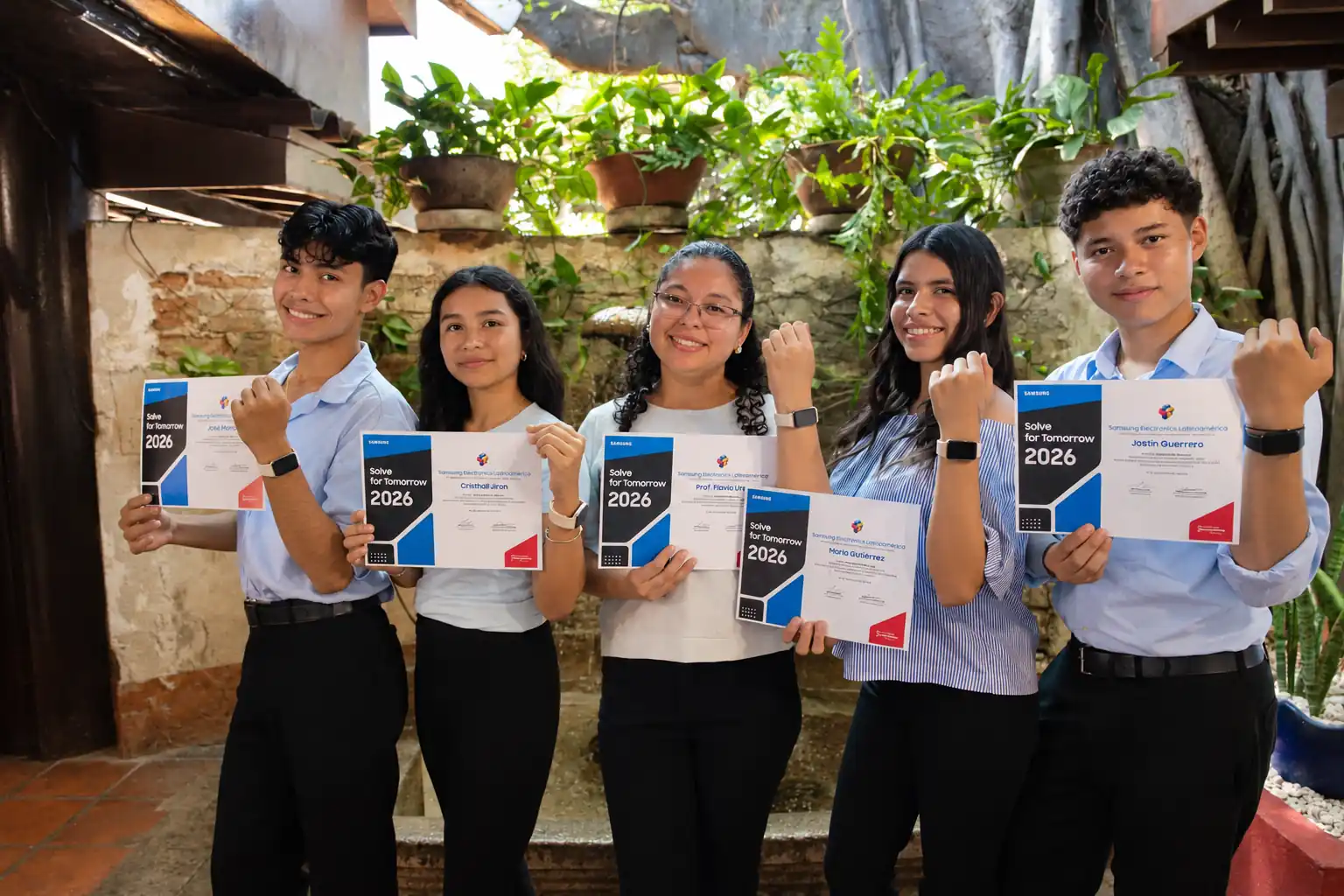 Cinco integrantes del equipo nicaragüense de Solve for Tomorrow 2026 sonríen y muestran sus certificados en un patio con plantas