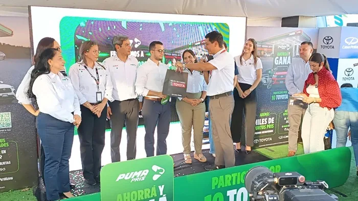 Grupo de profesionales en evento corporativo durante la entrega de un obsequio en el escenario.