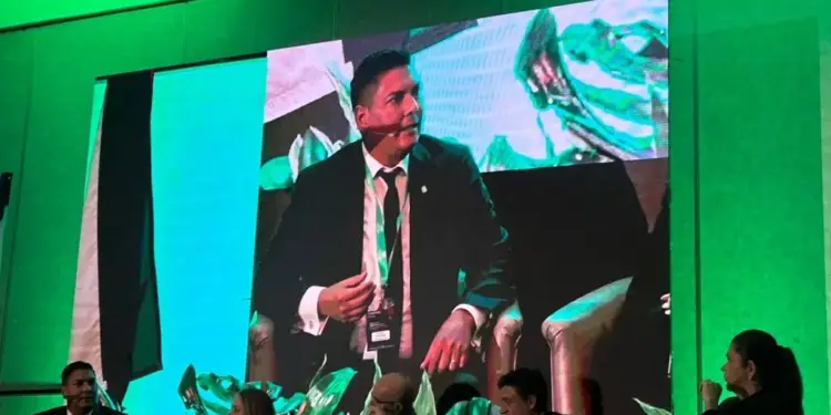 Panelistas en una conferencia de negocios frente a una gran pantalla que muestra a uno de los ponentes.