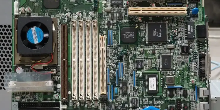 Vista superior de una placa base de computadora de circuito impreso verde con ranuras de expansión y un ventilador.