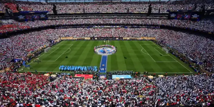Vista panorámica de un gran estadio lleno de espectadores durante un evento deportivo con cancha verde.