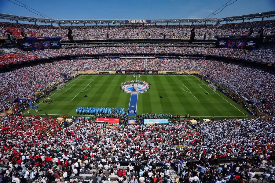 Vista panorámica de un gran estadio lleno de espectadores durante un evento deportivo con cancha verde.