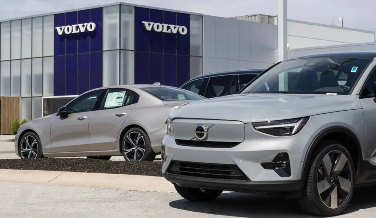 Vista frontal de un concesionario Volvo con dos autos modernos de color gris plateado estacionados afuera. Uno es un sedán y el otro es un SUV.